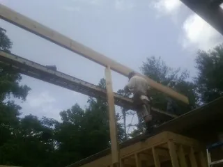 Carpenter setting a ridge beam over a new addition frame — Ice Dam Removal by Roofing Brothers in Monument Beach