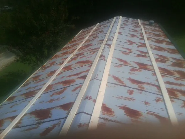Rusted metal roof panels with new wood purlins before replacement — Storm Damage Roof Repair in Monument Beach by Roofing Brothers