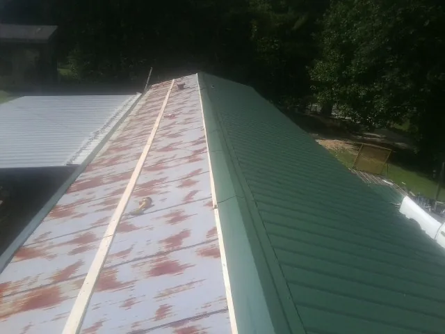Old rusted panels beside newly installed green metal roofing — Wind Damage Roof Repair by Roofing Brothers in Monument Beach