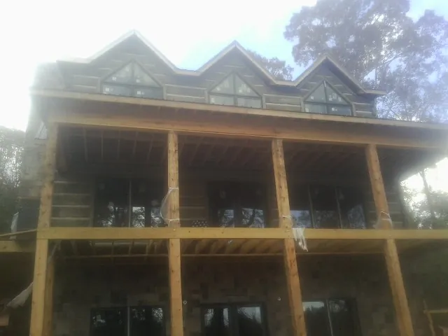 Dormers and porch framing on a large log home under construction — Roof Coating work by our crew in Monument Beach