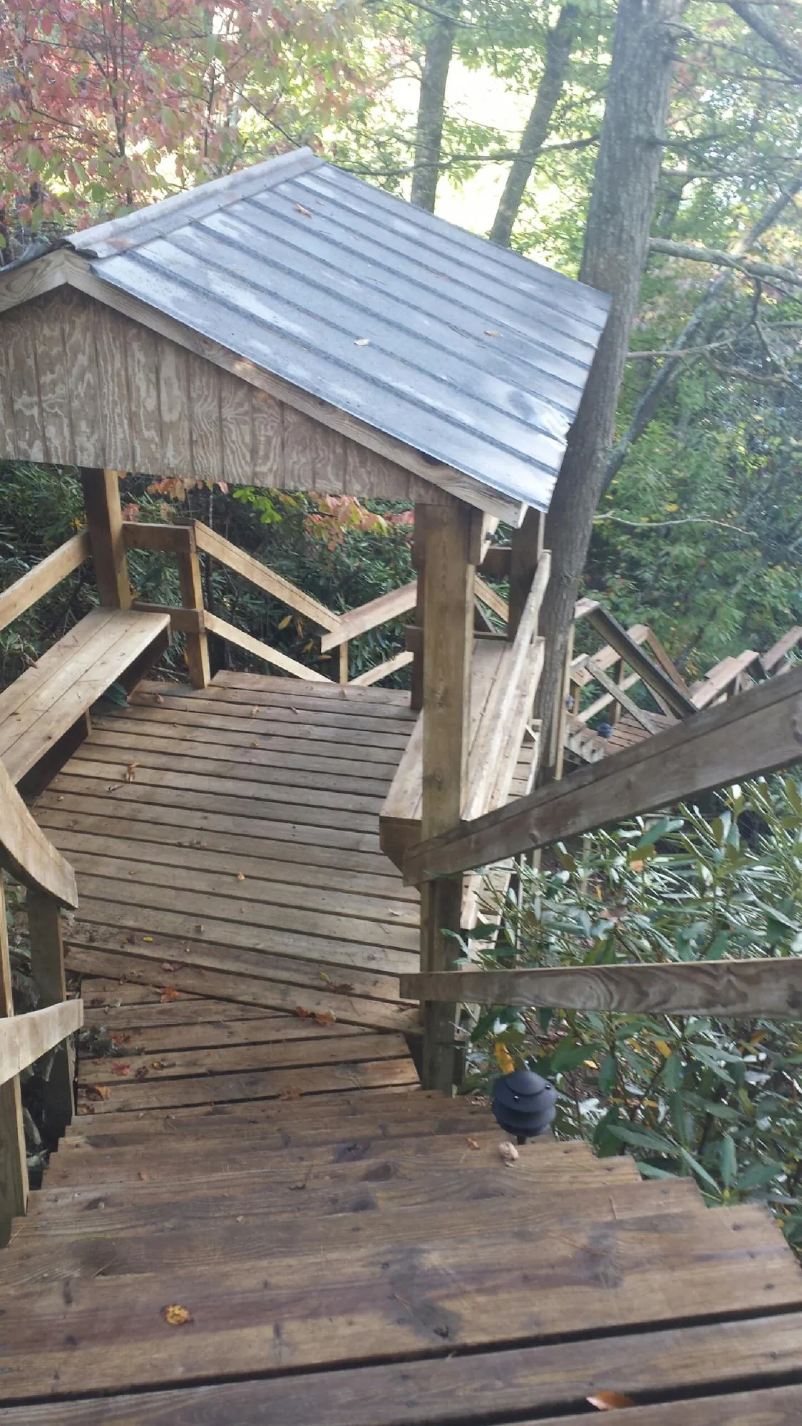 Metal roofed shelter over wooden steps on a wooded walkway — Skylight Repair & Installation work by our crew in Monument Beach