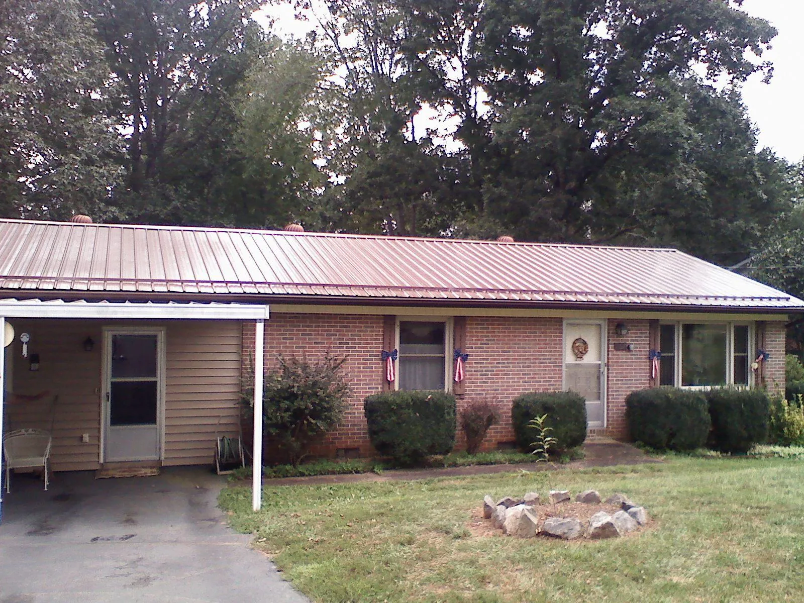 Bronze metal roof and carport on a brick ranch home — Roof Repair work by our crew in Monument Beach