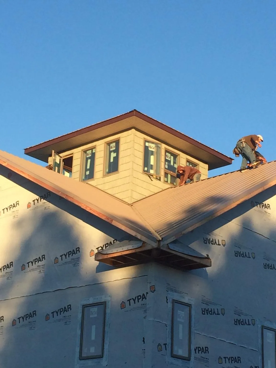 Roofers working around a rooftop cupola on a new metal roof at sunset — Roof Waterproofing in Monument Beach by Roofing Brothers